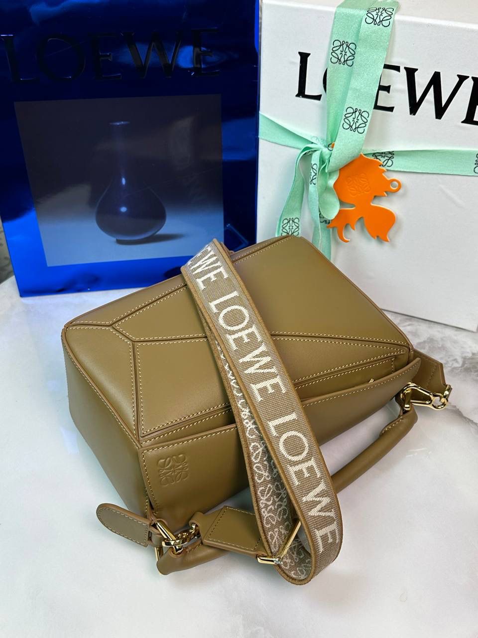 🅰️小号 𝗣𝘂𝘇𝘇𝗹𝗲最新版本❤️ ——（缎面/织带款） ✅经典拼图系列，不规则立体几何设计，最具辨识度的立体廓形和几何美学，顶级进口小牛皮搭配德国沙菲线，独家定制五金，𝗬𝗞𝗞拉链拉头 ✅容量超大，颜值高，四季百搭，新款自带可拆卸𝗟𝗢𝗘𝗪𝗘织带宽肩带‼️ 尺寸：𝟐𝟒-𝟏𝟎.𝟓-𝟏𝟔.𝟓𝐜𝐦 款号：061609织带橡木棕