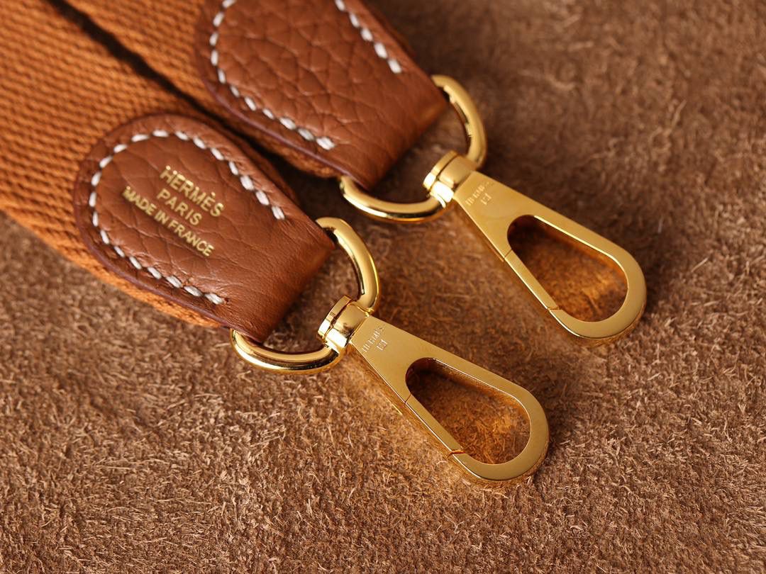 HERMES爱马仕Evelyne 16伊芙琳金棕金扣👜✨ TaurillonMaurice 小公牛皮 尺寸：16*18*5cm 爱马仕Evelyne伊芙琳 Evelyne包的设计灵感来自于一种名为“马鞍袋”的马具袋，这是一种常用于骑手和马车夫的袋子，用于储存和运输马具和其他必需品。 爱马仕将这种马具袋的经典元素与品牌的手工艺传统相结合，打造出了具有时尚感和功能性的包包。 因此，伊芙琳包不仅是一款实用的手提包，同时也代表着品牌深厚的历史和文化传统❤️