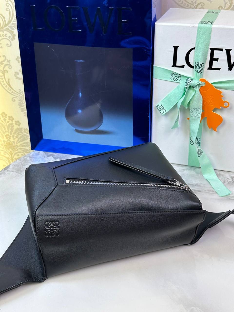 ⭐️最新升级版𝟮.𝟬-𝗣𝘂𝘇𝘇𝗹𝗲腰包⭐️ （黑色 到货‼️） 尺寸：𝟮𝟰-𝟭𝟬.𝟱-𝟭𝟲𝗰𝗺 款号：052343 👉🏻长方体形状和精确的切割技巧创造出Puzzle 腰包以及独特的几何线条成为 “Loe罗家”的著名代表作~ 👉🏻金属搭扣开合，刻有标志logo徽标，可调节肩带，翻盖大容量插袋和一个外部拉链口袋，🐂柔软细腻napa小牛皮，正品Ykk五金，Anagram压纹，人字纹棉麻帆布内里 👉🏻（男女♀♂同款）大小非常合适。胸包、背包、单肩、斜挎 腰包五种背法任你解锁🔒 👉🏻 （独家背景➕独家品质➕独家包装➕独家控制对版细节📦➕精致全套礼盒套装❤️） 重点：让你花最少的钱💰体验最大的仪式感❤️