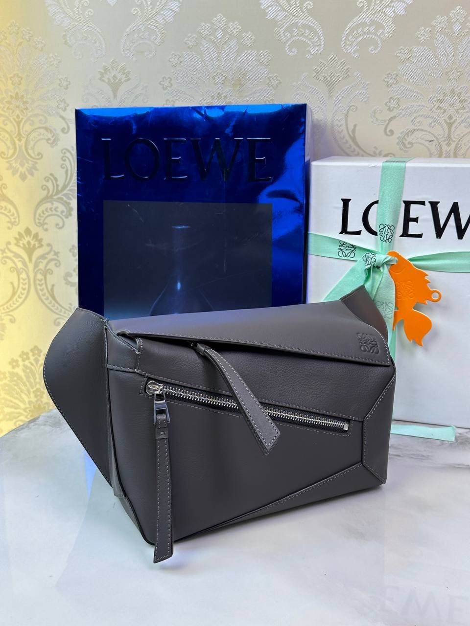 ⭐️最新升级版𝟮.𝟬-𝗣𝘂𝘇𝘇𝗹𝗲腰包⭐️ （深灰色 到货‼️） 尺寸：𝟮𝟰-𝟭𝟬.𝟱-𝟭𝟲𝗰𝗺 款号：052343 👉🏻长方体形状和精确的切割技巧创造出Puzzle 腰包以及独特的几何线条成为 “Loe罗家”的著名代表作~ 👉🏻金属搭扣开合，刻有标志logo徽标，可调节肩带，翻盖大容量插袋和一个外部拉链口袋，🐂柔软细腻napa小牛皮，正品Ykk五金，Anagram压纹，人字纹棉麻帆布内里 👉🏻（男女♀♂同款）大小非常合适。胸包、背包、单肩、斜挎 腰包五种背法任你解锁🔒 👉🏻 （独家背景➕独家品质➕独家包装➕独家控制对版细节📦➕精致全套礼盒套装❤️） 重点：让你花最少的钱💰体验最大的仪式感❤️