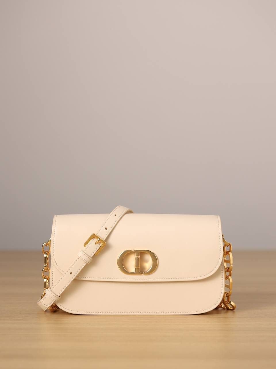 30 MONTAIGNE AVENUE 手袋 灰象牙色光面牛皮革👜✨ 独家渠道货 独家蒙田腋下包白色珐琅扣 尺寸：22.5 x 12.5 x 6.5 厘米 这款 30 Montaigne Avenue 手袋采用典雅的设计，提升此经典系列的格调。 采用黑色光面牛皮革精心制作，圆角翻盖曲线精致，饰以复古金色饰面金属 CD 扣环，灵感源自 Christian Dior 香水瓶的封口。 背面饰以压花 30 Montaigne 标志，搭配由金色饰面金属和与皮革同色调的珐琅链环交替组成的经典链条。 褶层设计，空间宽敞，廓形精致，可手提，肩背或斜挎。