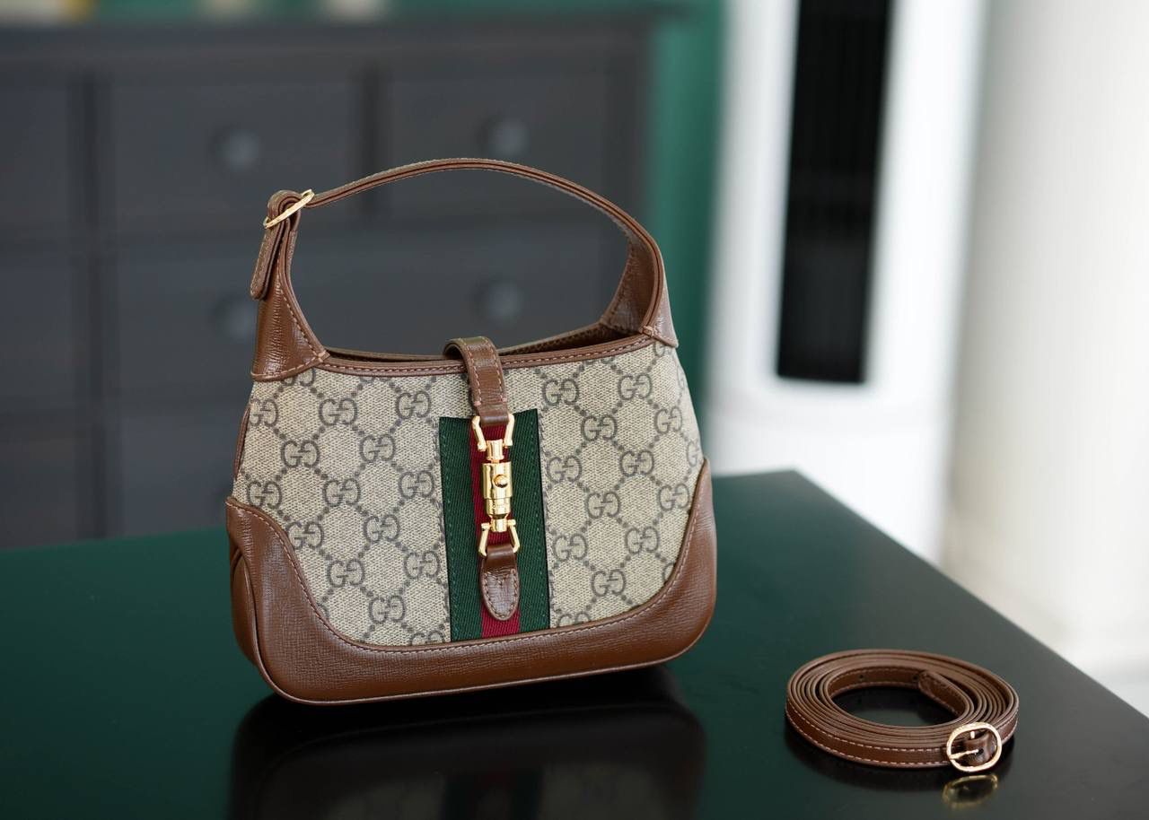 🥯GG Jackie 1961系列迷你手袋 棕色19cm 正品售价,500 经典𝙅𝙖𝙘𝙠𝙞𝙚是爱豆们最近的心头好 mini可爱程度超出我的想像 绿红织带复古设计 将60年代的气息与现代的时尚融合交汇 不仅让人感受到浓郁的复古美感， 还多了时尚潮流的气息，结合起来真的是非常赞！！！ 两条肩带设计，腋下背单肩背多风格背法~ 官方款号 637092 尺寸：19x13x3cm