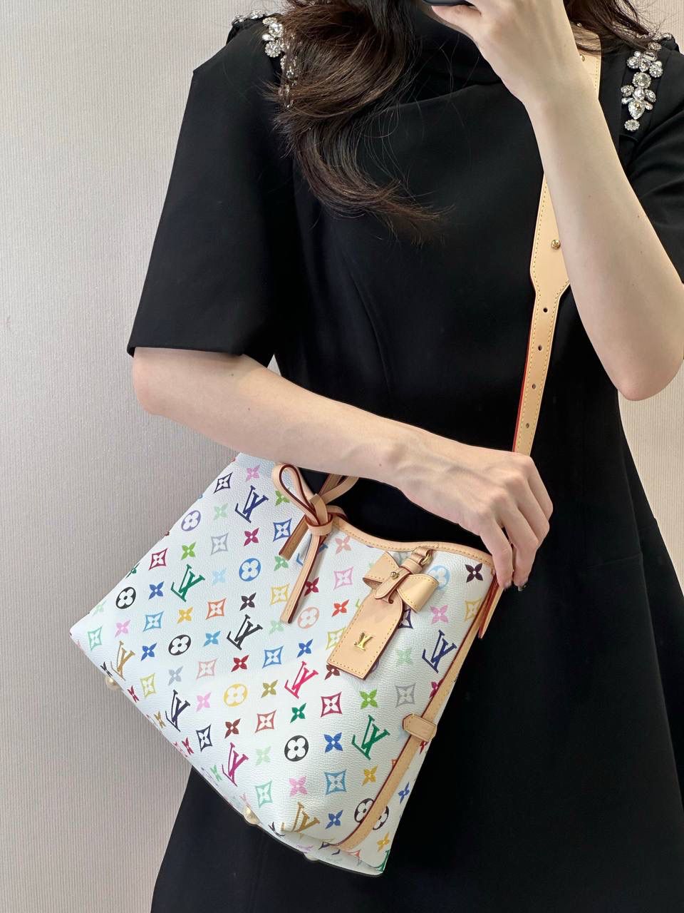 LV 白三彩 Carryall 👜✨ 这是那种—— 一背上街，别人会多看你两眼的包 🌈 白底三彩像把颜色撒进 Monogram 里， 樱花、熊猫跳出来那一刻， 整个包都在发光 ☀️ 不是甜腻，是很有态度的可爱。 Carryall BB 包型软软的、容量却很能装， 通勤不无聊，出游更加分。 蝴蝶结、链条点缀得刚刚好， 甜酷之间拿捏得很准。 如果你已经看腻普通老花， 那这只，就是春天给你的答案 🌸 📏 25 × 31 × 14 cm