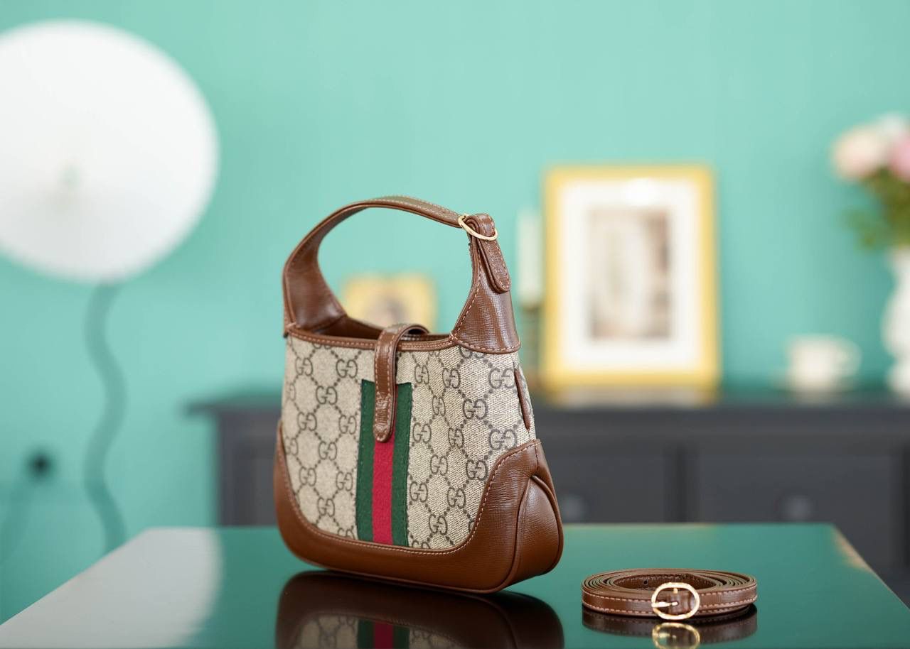 🥯GG Jackie 1961系列迷你手袋 棕色19cm 正品售价,500 经典𝙅𝙖𝙘𝙠𝙞𝙚是爱豆们最近的心头好 mini可爱程度超出我的想像 绿红织带复古设计 将60年代的气息与现代的时尚融合交汇 不仅让人感受到浓郁的复古美感， 还多了时尚潮流的气息，结合起来真的是非常赞！！！ 两条肩带设计，腋下背单肩背多风格背法~ 官方款号 637092 尺寸：19x13x3cm