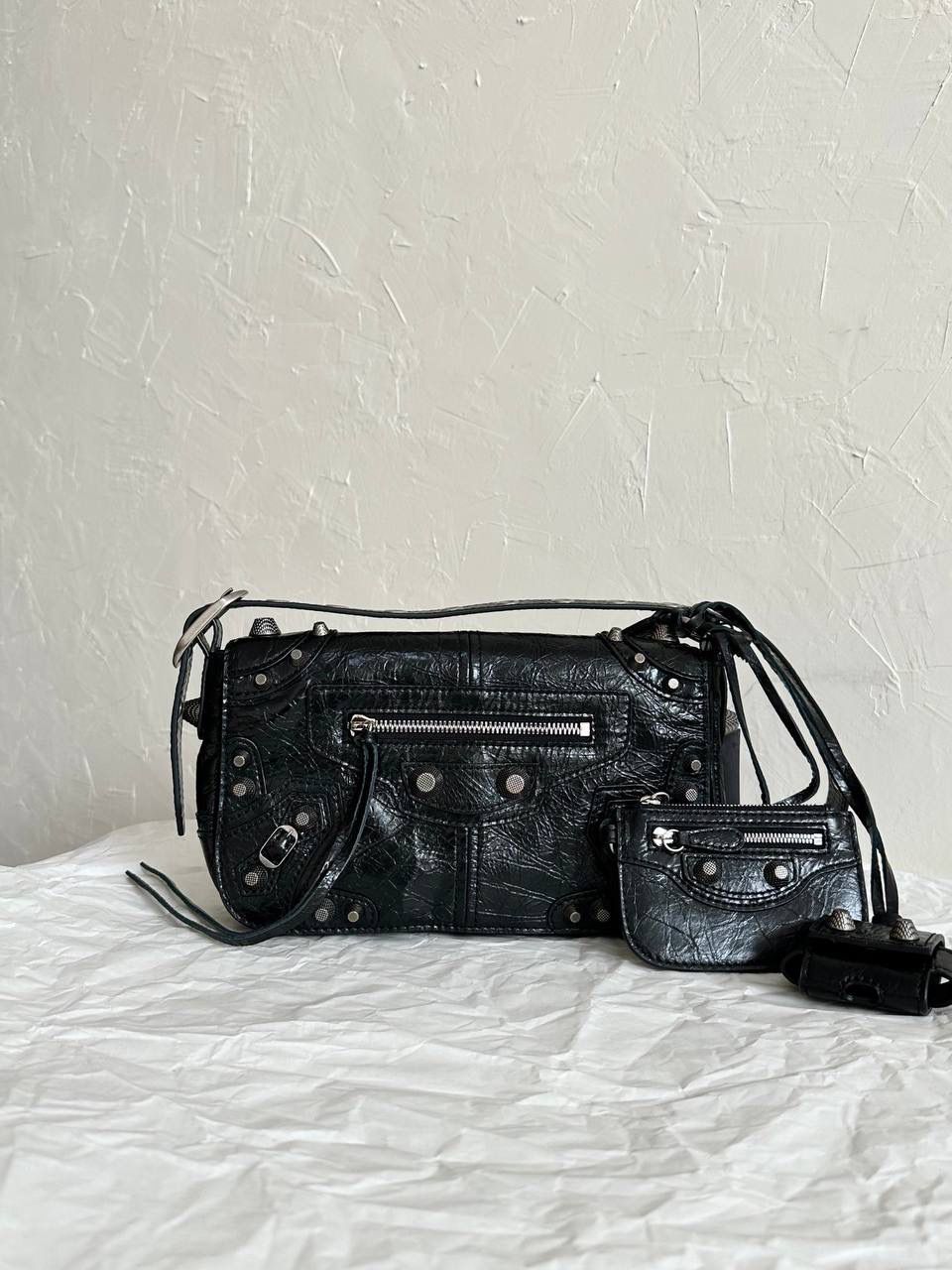 ba1enciaga le cagole机车翻盖包👜❤️‍🩹 现在的男生打扮得越来越年轻时髦 这种时髦的男包简直像珍宝一样难得 他们家真的太懂现在的潮男潮女的需求了 这只翻盖的感觉更特别！ 而且用起来更方便，打开盖子就行 包身上吊着的卡包和耳机包 砖柜单独买一个都要k➕！！ 省大钱了！ 咱家的油蜡皮爆裂感老客都知道的 纹路必须狠狠的"裂"开来 那种平滑的便宜的不对版皮请靠边～ ZP开发⚠️所有细节一致 24×14×5cm719082m