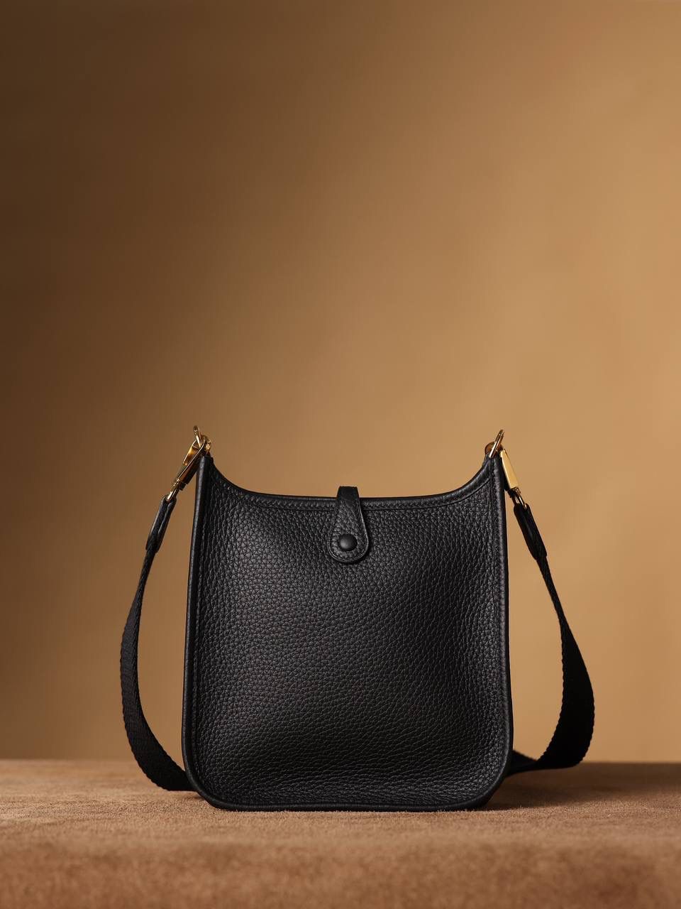 HERMES爱马仕Evelyne 16伊芙琳黑色金扣👜✨ TaurillonMaurice 小公牛皮 尺寸：16*18*5cm 爱马仕Evelyne伊芙琳 Evelyne包的设计灵感来自于一种名为“马鞍袋”的马具袋，这是一种常用于骑手和马车夫的袋子，用于储存和运输马具和其他必需品。 爱马仕将这种马具袋的经典元素与品牌的手工艺传统相结合，打造出了具有时尚感和功能性的包包。 因此，伊芙琳包不仅是一款实用的手提包，同时也代表着品牌深厚的历史和文化传统❤️