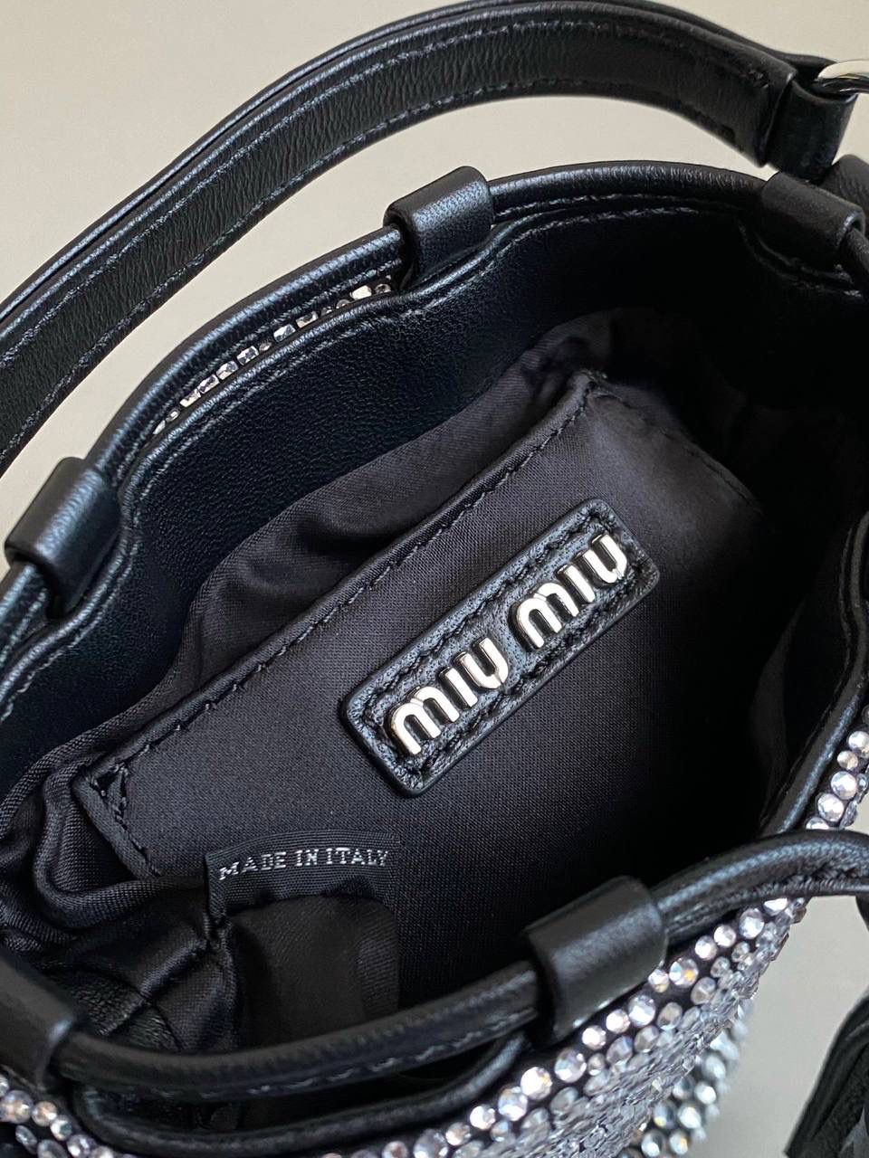 🈶钻石黑 𝗠𝗶𝘂𝗠𝗶𝘂满钻水桶包 blingbling的又是多少女生的心头爱 整个包身贴满水晶，搭配软绵绵的小羊皮， 在光线下非常闪✨不管是日常约会， 节日派对 晚宴都会是人群中的抢眼包 15×17×11cm F0053m