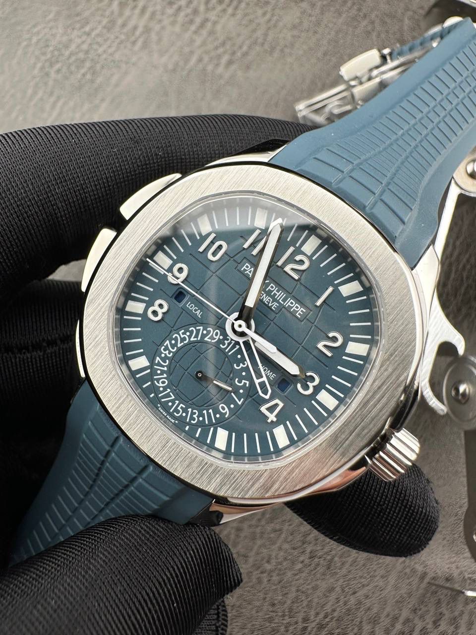 百达翡丽Aquanaut系列😎 【表壳】40.8MM表径，不锈钢材质，圆润的八角壳型恰到好处，表壳左侧的鲨鱼鳍型设计，是可以前后快调中央镂空时针的按钮，这枚指针可以用来指示第二时区时间。 【表盘】黑色浮雕表盘，金属立体字块，覆荧光涂层时标。3、9点钟分别显示”HOME”与”LOCAL”的方形昼夜视窗，蓝白二色各自代表晚上与白天，6点钟位置是指针式的日期盘。 【机芯】成功实现百达翡丽5164A-001内载的324 SC FUS自动上链机芯功能，大三针基础机芯上搭载两地时间模组。 配有休闲气息的Tropical表带，正是为年轻世代所准备的奢华运动表。