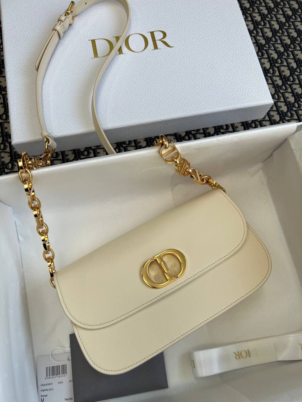 30 MONTAIGNE AVENUE 手袋 灰象牙色光面牛皮革👜✨ 独家渠道货 独家蒙田腋下包白色珐琅扣 尺寸：22.5 x 12.5 x 6.5 厘米 这款 30 Montaigne Avenue 手袋采用典雅的设计，提升此经典系列的格调。 采用黑色光面牛皮革精心制作，圆角翻盖曲线精致，饰以复古金色饰面金属 CD 扣环，灵感源自 Christian Dior 香水瓶的封口。 背面饰以压花 30 Montaigne 标志，搭配由金色饰面金属和与皮革同色调的珐琅链环交替组成的经典链条。 褶层设计，空间宽敞，廓形精致，可手提，肩背或斜挎。