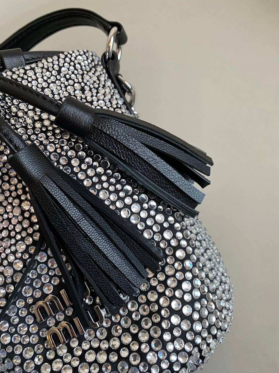 🈶钻石黑 𝗠𝗶𝘂𝗠𝗶𝘂满钻水桶包 blingbling的又是多少女生的心头爱 整个包身贴满水晶，搭配软绵绵的小羊皮， 在光线下非常闪✨不管是日常约会， 节日派对 晚宴都会是人群中的抢眼包 15×17×11cm F0053m