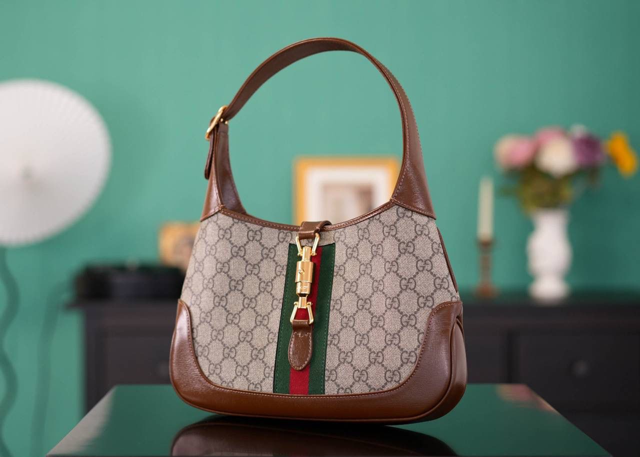 🥯GG Jackie 1961系列小号手袋 棕色28cm 正品售价,200 经典𝙅𝙖𝙘𝙠𝙞𝙚是爱豆们最近的心头好 绿红织带复古设计 将60年代的气息与现代的时尚融合交汇 不仅让人感受到浓郁的复古美感， 还多了时尚潮流的气息，结合起来真的是非常赞！！！ 两条肩带设计，腋下背单肩背多风格背法~ 官方款号 636706 尺寸：28x19x4.5cm