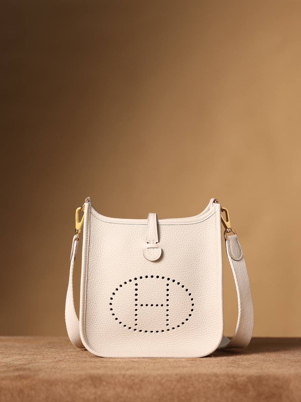 HERMES爱马仕Evelyne 16伊芙琳奶昔白金扣👜✨ TaurillonMaurice 小公牛皮 尺寸：16*18*5cm 爱马仕Evelyne伊芙琳 Evelyne包的设计灵感来自于一种名为“马鞍袋”的马具袋，这是一种常用于骑手和马车夫的袋子，用于储存和运输马具和其他必需品。 爱马仕将这种马具袋的经典元素与品牌的手工艺传统相结合，打造出了具有时尚感和功能性的包包。 因此，伊芙琳包不仅是一款实用的手提包，同时也代表着品牌深厚的历史和文化传统❤️