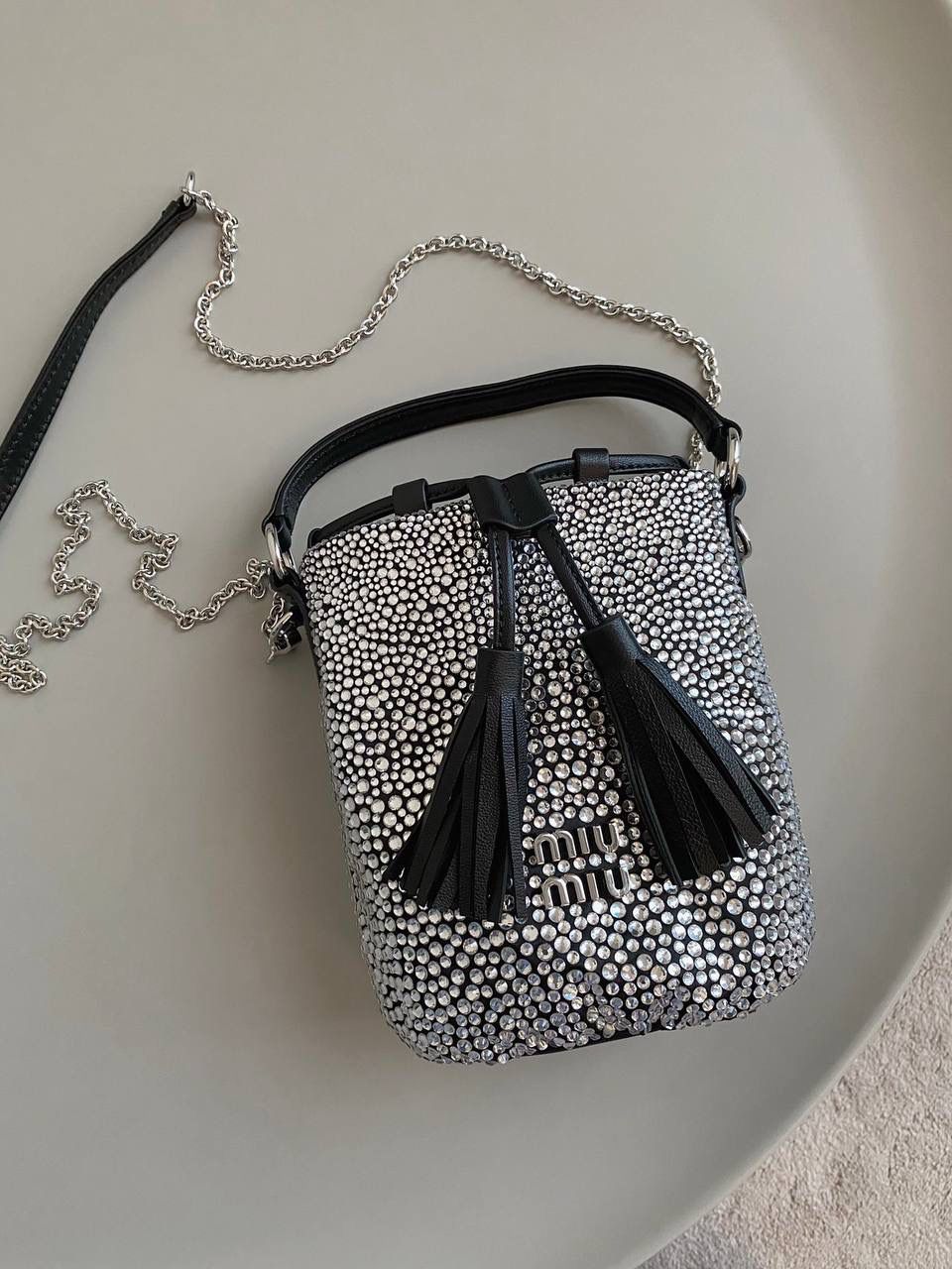 🈶钻石黑 𝗠𝗶𝘂𝗠𝗶𝘂满钻水桶包 blingbling的又是多少女生的心头爱 整个包身贴满水晶，搭配软绵绵的小羊皮， 在光线下非常闪✨不管是日常约会， 节日派对 晚宴都会是人群中的抢眼包 15×17×11cm F0053m
