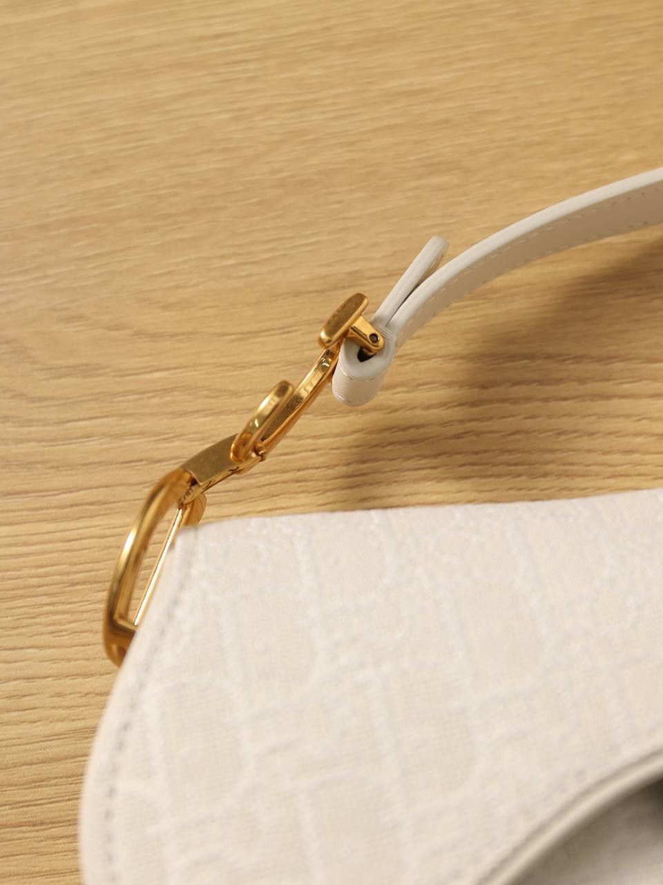 马鞍包白色小号 独家渠道原厂货 尺寸：21 x 18 x 5 厘米 这款标志性的马鞍包由玛丽亚·嘉茜娅·蔻丽 (Maria Grazia Chiuri) 设计，重新演绎经典款式。 马镫“D”形吊饰和马鞍翻盖彰显品牌经典设计，搭配磁铁搭扣，手柄两端饰以“CD”标志。 采用白色提花 Oblique 印花面料制作，饰以复古金色饰面金属配件。 这款马鞍包可手提或肩背，可搭配不同的肩带彰显个性。 马镫“D”形吊饰和磁铁搭扣开合 手柄饰以“CD”标志 内部口袋 后侧口袋 内含防尘袋