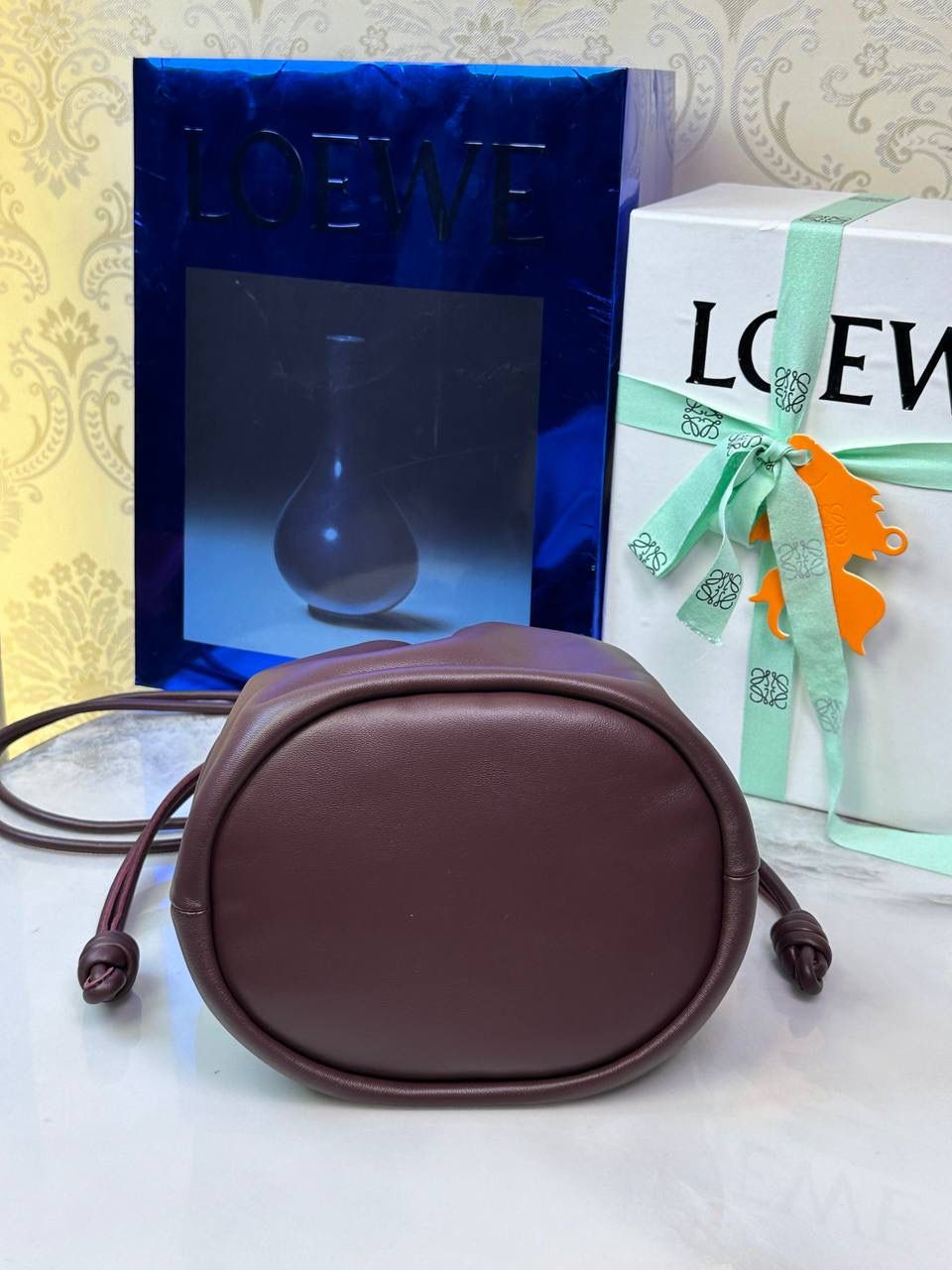 🎈链条款𝙁𝙡𝙖𝙢𝙚𝙣𝙘𝙤 𝙋𝙪𝙧𝙨𝙚水桶羊皮 ——【酒红色】 尺寸：𝟑𝟐-𝟏𝟕-𝟐𝟒𝐜𝐦 编码：062406 👉🏻延续福袋收缩绳褶皱设计，全新推出水桶造型，羊皮包身手感细腻柔软❤️ 👉🏻链条肩带➕皮肩带的双肩带设计，时尚百搭，给足了集美们多样化的选择。肩带可拆卸可调节，磁扣开合，正面烫金𝙇𝙤𝙜𝙤，呈现出高贵典雅的视觉感😍 👉🏻独家背景➕独家品质➕独家全套砖柜礼盒套装，市场高端品质皆在我手✌🏻