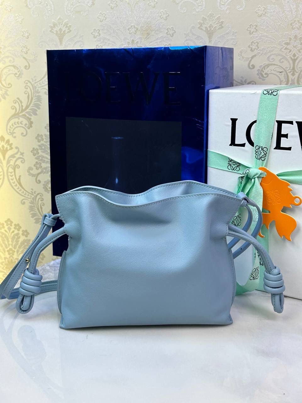 Flamenco clutch-NEW ✦迷你✦ 尺寸：𝟐𝟐.𝟓-𝟏𝟖-𝟗𝐜𝐦 型号：052030灰蓝色 ❤️mini flamenco clutch bag 可手拿亦可优雅斜挎 云朵般温暖亦轻盈的造型如此简单，💯耐看💯不会out的款式！ ❤️包袋采用进口小牛皮，手感如羊皮般细腻柔软，却比羊皮更加结实耐用，麂皮内衬 ❤️品牌标志性绳结设计，收紧袋口就是小福袋造型，超Q，看着不大实际超会装😇