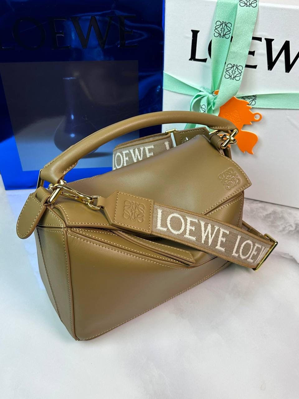 🅰️小号 𝗣𝘂𝘇𝘇𝗹𝗲最新版本❤️ ——（缎面/织带款） ✅经典拼图系列，不规则立体几何设计，最具辨识度的立体廓形和几何美学，顶级进口小牛皮搭配德国沙菲线，独家定制五金，𝗬𝗞𝗞拉链拉头 ✅容量超大，颜值高，四季百搭，新款自带可拆卸𝗟𝗢𝗘𝗪𝗘织带宽肩带‼️ 尺寸：𝟐𝟒-𝟏𝟎.𝟓-𝟏𝟔.𝟓𝐜𝐦 款号：061609织带橡木棕