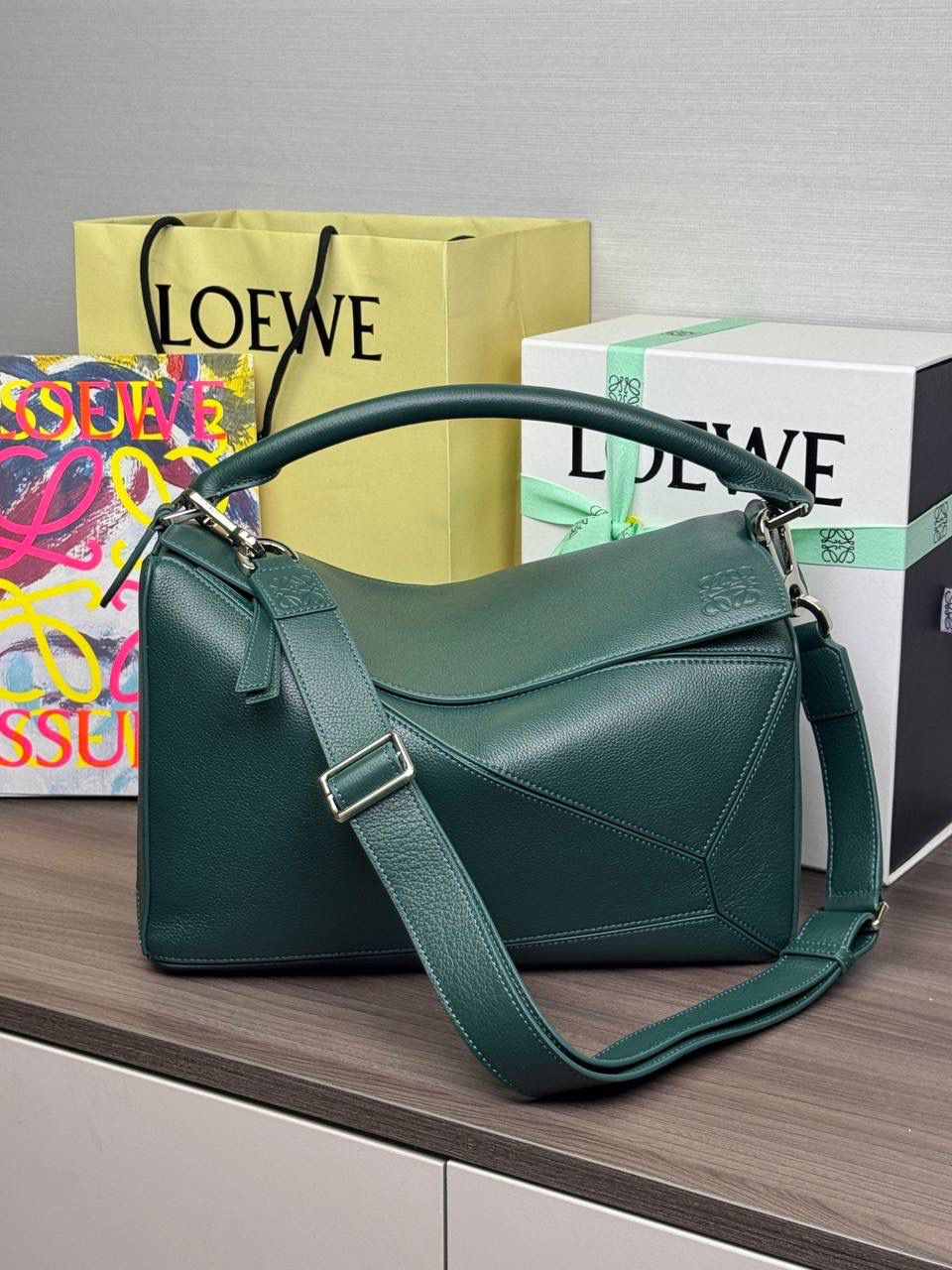 🎈【全钢】大号鹿皮𝘗𝘶𝘻𝘻𝘭𝘦* ——【👉🏻常青色到货✅】 尺寸：𝟑𝟐.𝟓-𝟏𝟒.𝟓-𝟐𝟑.𝟓𝐜𝐦 编码：260403 【配全套包装】 ❤️经典拼图系列•不规则立体几何设计•最具辨识度的立体廓形和几何美学•顶级进口皮搭配德国沙菲线•独家定制五金•𝗬𝗞𝗞拉链拉头。 ❤️该款大号采用鹿皮革制成•绒面内里•搭配一条可拆卸可调节的皮肩带•肩背斜挎或手提多样化背法。