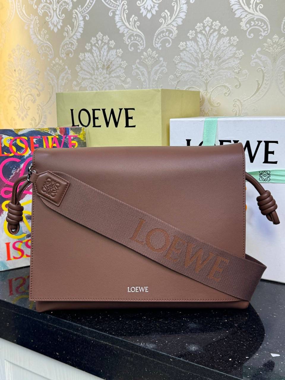 【全皮布朗尼色】 𝙇𝙤𝙚𝙬𝙚 𝙁𝙡𝙖𝙢𝙚𝙣𝙘𝙤 𝙎𝙖𝙩𝙘𝙝𝙚𝙡 福袋款邮差包 ➕刺绣🅾️字母宽肩带 编码：062404 尺寸：𝟑𝟒-𝟏𝟐-𝟐𝟒𝐜𝐦 新款以经典福袋收缩打结为元素，采用内部麂皮➕外部进口小牛皮➕刺绣字母宽肩带的精致搭配打造全新升级款邮差包🅰️，可斜挎、肩背和手提，超大容量满足日常所需🎈