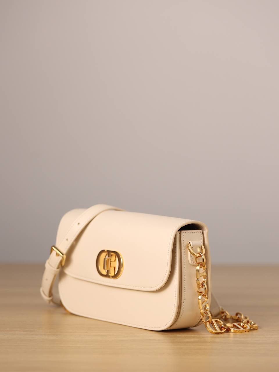 30 MONTAIGNE AVENUE 手袋 灰象牙色光面牛皮革👜✨ 独家渠道货 独家蒙田腋下包白色珐琅扣 尺寸：22.5 x 12.5 x 6.5 厘米 这款 30 Montaigne Avenue 手袋采用典雅的设计，提升此经典系列的格调。 采用黑色光面牛皮革精心制作，圆角翻盖曲线精致，饰以复古金色饰面金属 CD 扣环，灵感源自 Christian Dior 香水瓶的封口。 背面饰以压花 30 Montaigne 标志，搭配由金色饰面金属和与皮革同色调的珐琅链环交替组成的经典链条。 褶层设计，空间宽敞，廓形精致，可手提，肩背或斜挎。