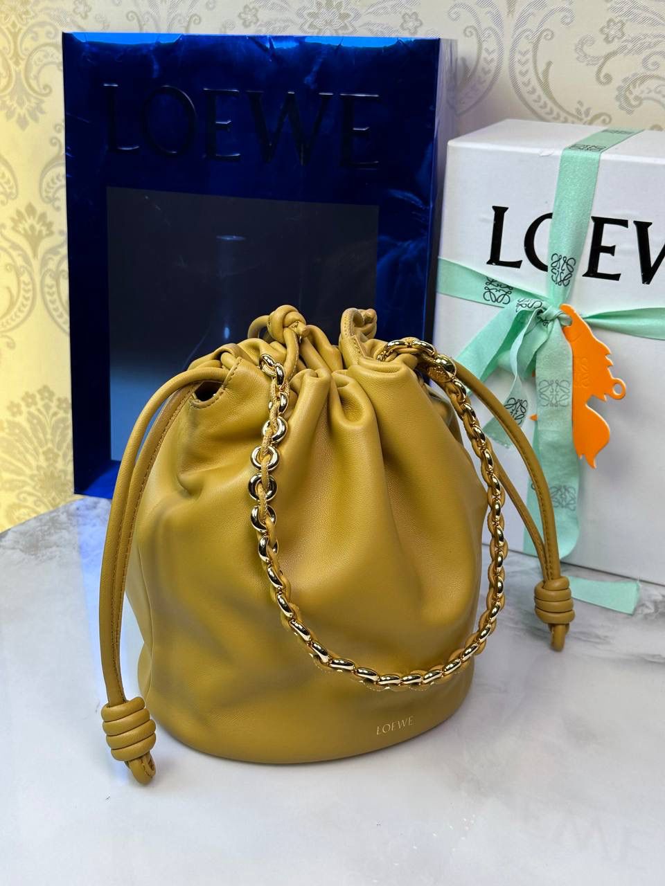 🎈链条款𝙁𝙡𝙖𝙢𝙚𝙣𝙘𝙤 𝙋𝙪𝙧𝙨𝙚水桶羊皮 ——【沙漠黄】 尺寸：𝟑𝟐-𝟏𝟕-𝟐𝟒𝐜𝐦 编码：062406 👉🏻延续福袋收缩绳褶皱设计，全新推出水桶造型，羊皮包身手感细腻柔软❤️ 👉🏻链条肩带➕皮肩带的双肩带设计，时尚百搭，给足了集美们多样化的选择。肩带可拆卸可调节，磁扣开合，正面烫金𝙇𝙤𝙜𝙤，呈现出高贵典雅的视觉感😍 👉🏻独家背景➕独家品质➕独家全套砖柜礼盒套装，市场高端品质皆在我手✌🏻