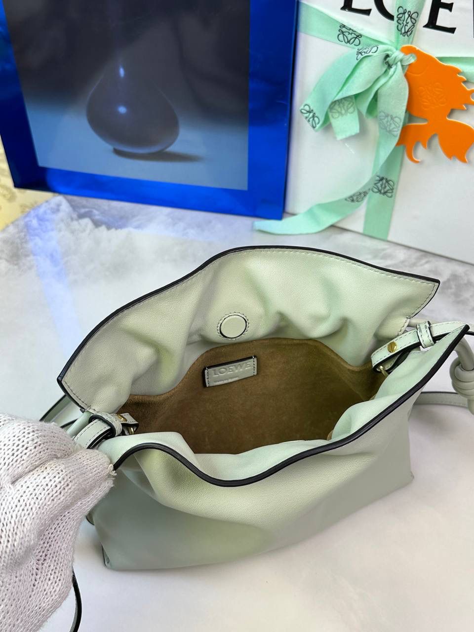 Flamenco clutch-NEW ✦迷你✦ 尺寸：𝟐𝟐.𝟓-𝟏𝟖-𝟗𝐜𝐦 型号：052030亮灰绿 ❤️mini flamenco clutch bag 可手拿亦可优雅斜挎 云朵般温暖亦轻盈的造型如此简单，💯耐看💯不会out的款式！ ❤️包袋采用进口小牛皮，手感如羊皮般细腻柔软，却比羊皮更加结实耐用，麂皮内衬 ❤️品牌标志性绳结设计，收紧袋口就是小福袋造型，超Q，看着不大实际超会装😇