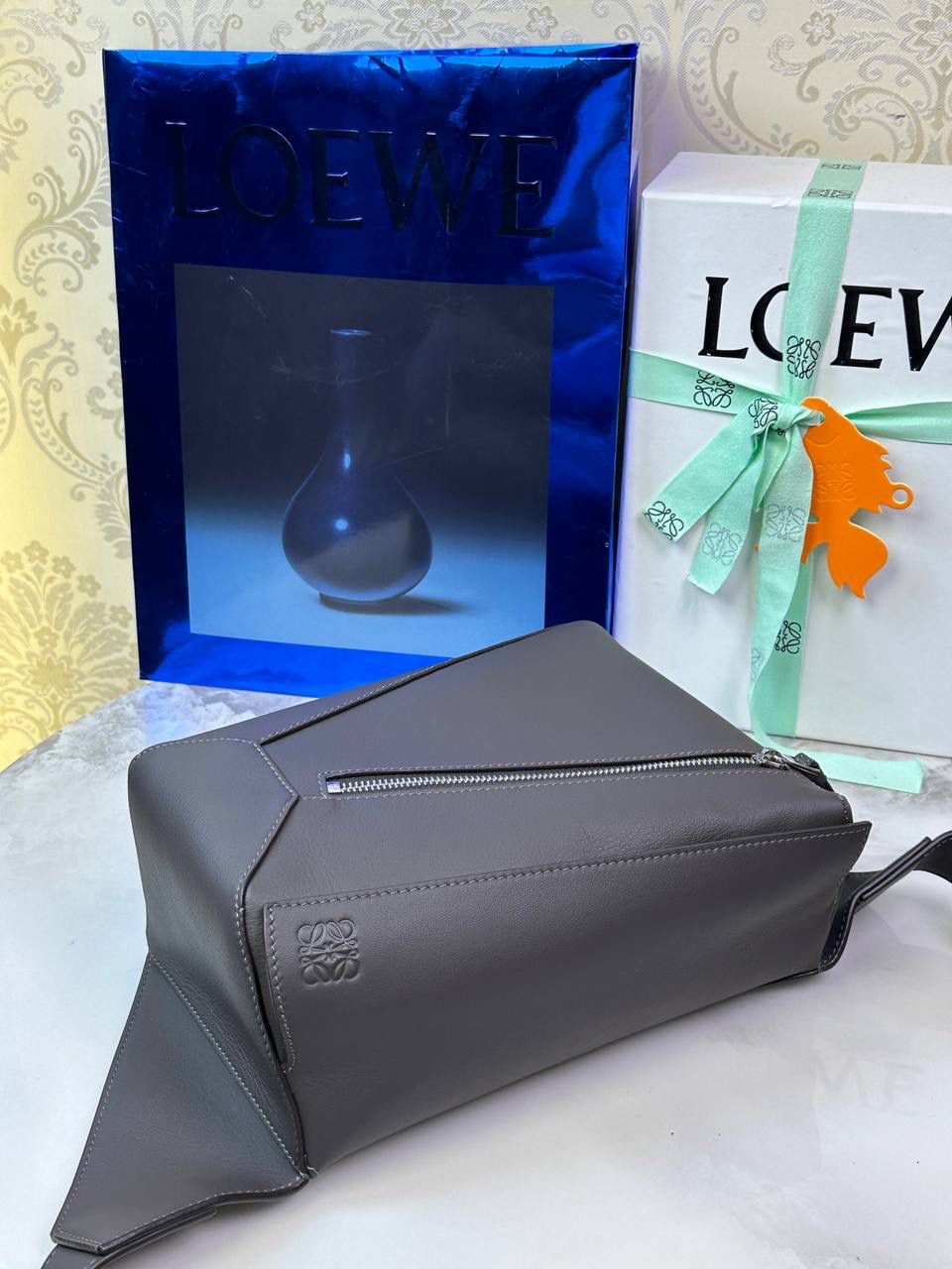 ⭐️最新升级版𝟮.𝟬-𝗣𝘂𝘇𝘇𝗹𝗲腰包⭐️ （深灰色 到货‼️） 尺寸：𝟮𝟰-𝟭𝟬.𝟱-𝟭𝟲𝗰𝗺 款号：052343 👉🏻长方体形状和精确的切割技巧创造出Puzzle 腰包以及独特的几何线条成为 “Loe罗家”的著名代表作~ 👉🏻金属搭扣开合，刻有标志logo徽标，可调节肩带，翻盖大容量插袋和一个外部拉链口袋，🐂柔软细腻napa小牛皮，正品Ykk五金，Anagram压纹，人字纹棉麻帆布内里 👉🏻（男女♀♂同款）大小非常合适。胸包、背包、单肩、斜挎 腰包五种背法任你解锁🔒 👉🏻 （独家背景➕独家品质➕独家包装➕独家控制对版细节📦➕精致全套礼盒套装❤️） 重点：让你花最少的钱💰体验最大的仪式感❤️