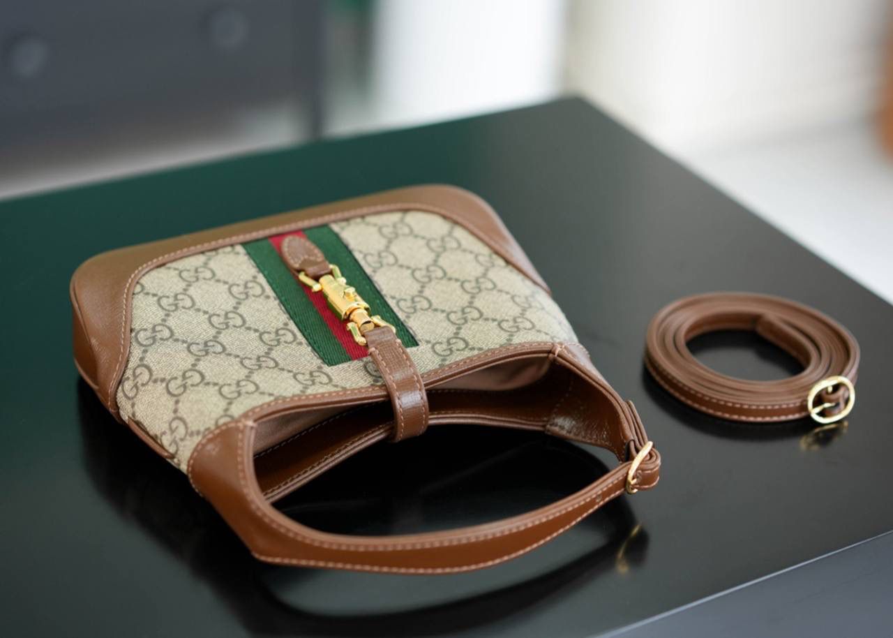 🥯GG Jackie 1961系列迷你手袋 棕色19cm 正品售价,500 经典𝙅𝙖𝙘𝙠𝙞𝙚是爱豆们最近的心头好 mini可爱程度超出我的想像 绿红织带复古设计 将60年代的气息与现代的时尚融合交汇 不仅让人感受到浓郁的复古美感， 还多了时尚潮流的气息，结合起来真的是非常赞！！！ 两条肩带设计，腋下背单肩背多风格背法~ 官方款号 637092 尺寸：19x13x3cm