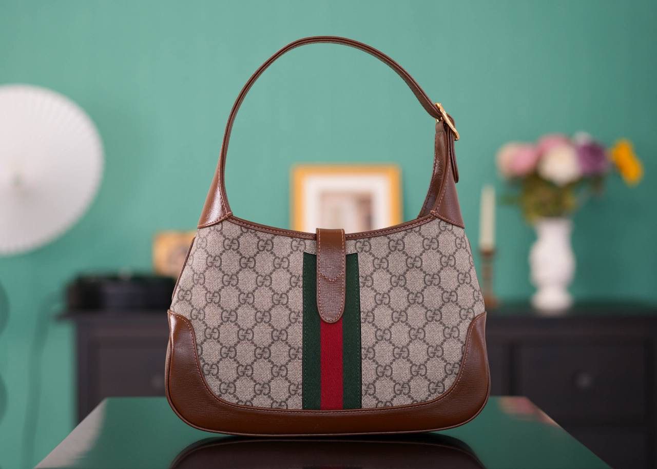 🥯GG Jackie 1961系列小号手袋 棕色28cm 正品售价,200 经典𝙅𝙖𝙘𝙠𝙞𝙚是爱豆们最近的心头好 绿红织带复古设计 将60年代的气息与现代的时尚融合交汇 不仅让人感受到浓郁的复古美感， 还多了时尚潮流的气息，结合起来真的是非常赞！！！ 两条肩带设计，腋下背单肩背多风格背法~ 官方款号 636706 尺寸：28x19x4.5cm