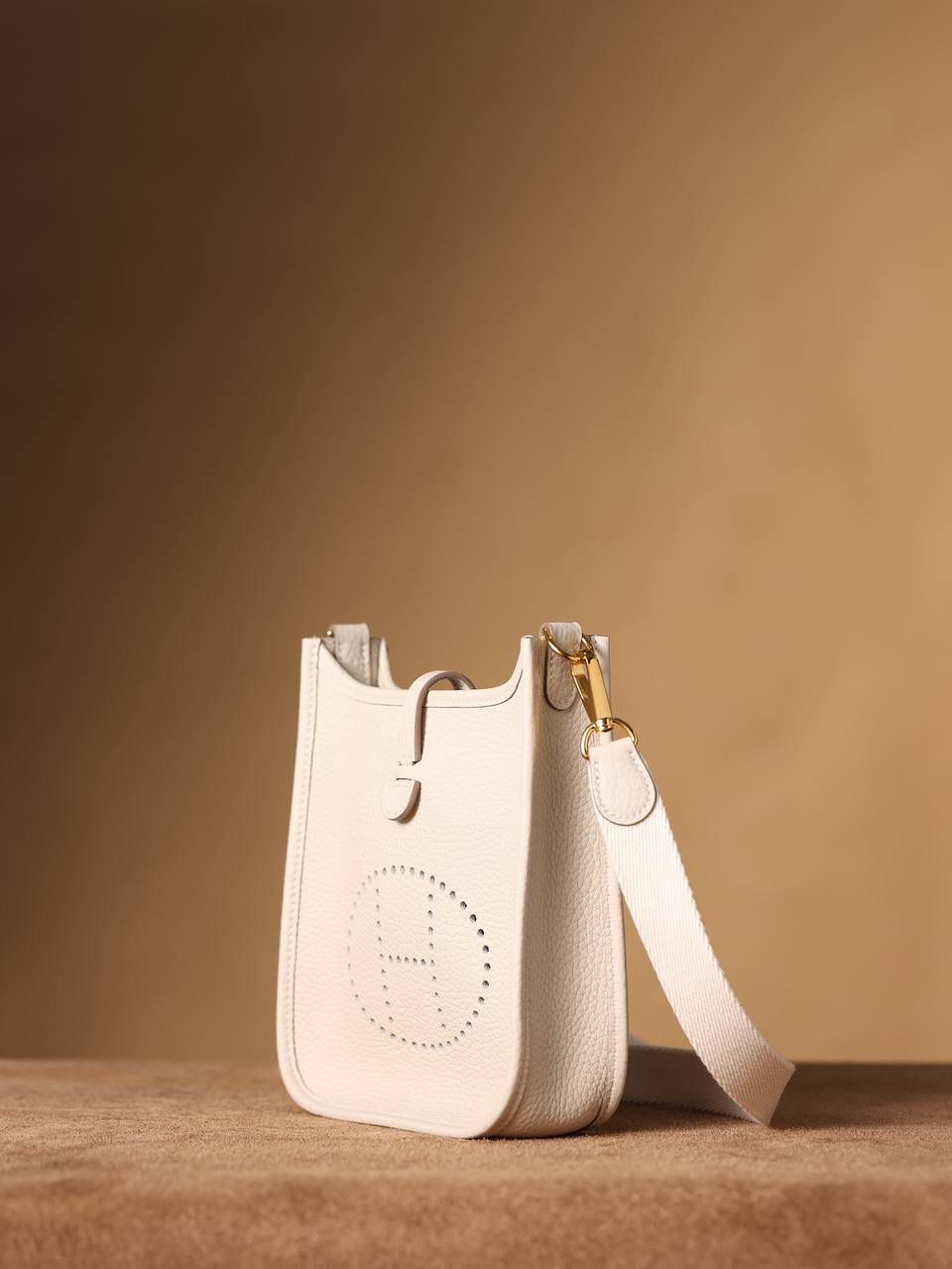 HERMES爱马仕Evelyne 16伊芙琳奶昔白金扣👜✨ TaurillonMaurice 小公牛皮 尺寸：16*18*5cm 爱马仕Evelyne伊芙琳 Evelyne包的设计灵感来自于一种名为“马鞍袋”的马具袋，这是一种常用于骑手和马车夫的袋子，用于储存和运输马具和其他必需品。 爱马仕将这种马具袋的经典元素与品牌的手工艺传统相结合，打造出了具有时尚感和功能性的包包。 因此，伊芙琳包不仅是一款实用的手提包，同时也代表着品牌深厚的历史和文化传统❤️