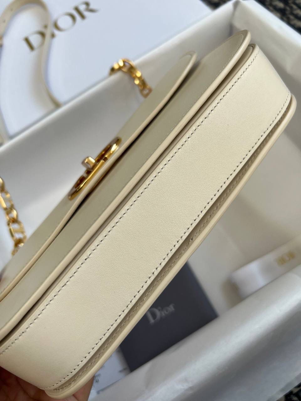 30 MONTAIGNE AVENUE 手袋 灰象牙色光面牛皮革👜✨ 独家渠道货 独家蒙田腋下包白色珐琅扣 尺寸：22.5 x 12.5 x 6.5 厘米 这款 30 Montaigne Avenue 手袋采用典雅的设计，提升此经典系列的格调。 采用黑色光面牛皮革精心制作，圆角翻盖曲线精致，饰以复古金色饰面金属 CD 扣环，灵感源自 Christian Dior 香水瓶的封口。 背面饰以压花 30 Montaigne 标志，搭配由金色饰面金属和与皮革同色调的珐琅链环交替组成的经典链条。 褶层设计，空间宽敞，廓形精致，可手提，肩背或斜挎。