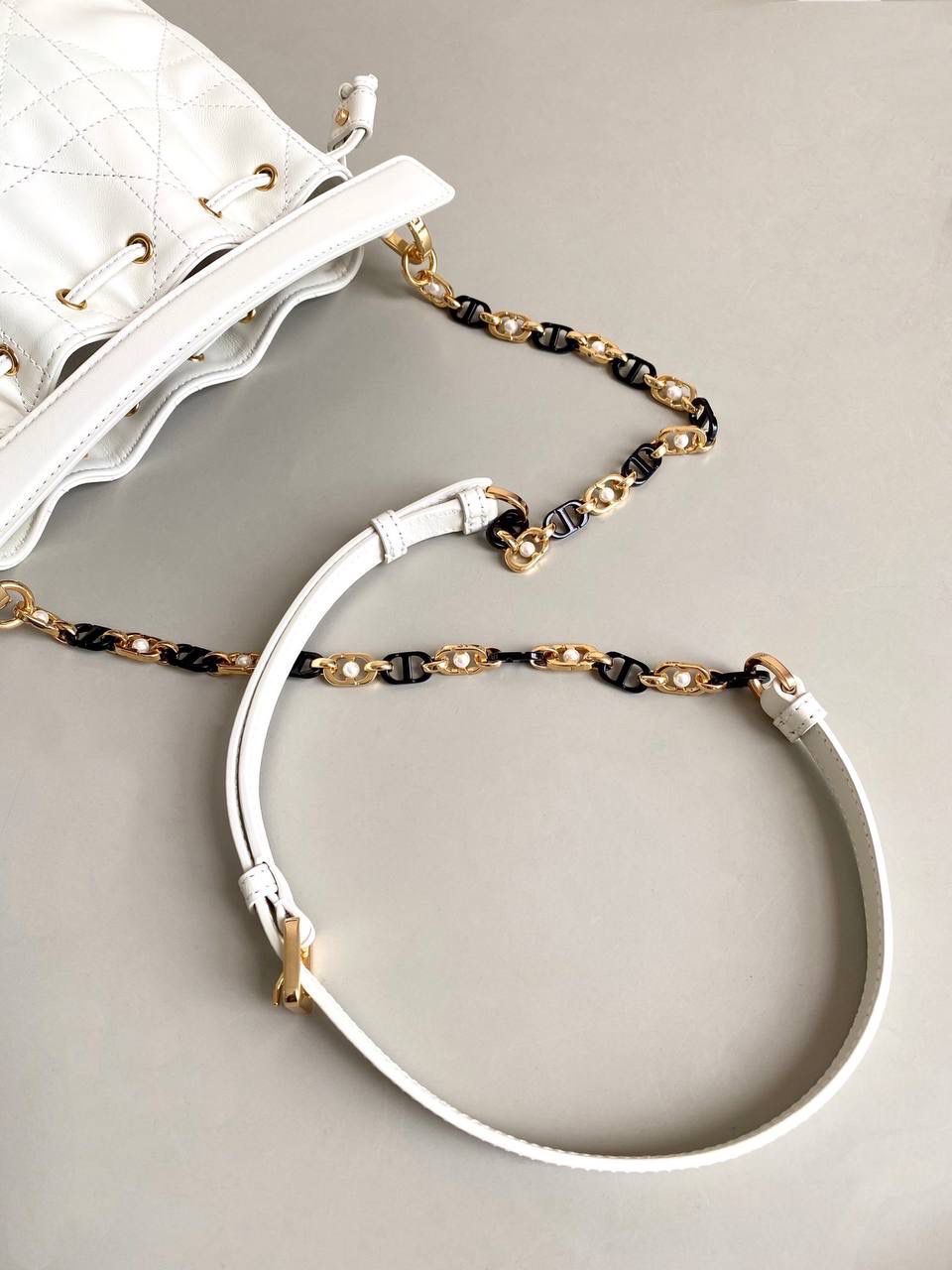 🈶白色，迷你 𝗗𝗜𝗢𝗥 𝗠𝗮𝗿𝗹𝗲𝗺𝗮水桶包 水桶包好的一点就是容量巨大！ D家新出的这只你不要看它小， 容量我真的超爱～ 风格依然是Jolie同系列的珍珠元素 极简的包身加拼色链条，精致耐看 经典藤格纹羊皮，皮质柔软有光泽 主要是实用，斜挎休闲 手拎乖巧精致， 适用于任何场合！ 绝对是你日常出勤率最高的一款 17×16×9cm #7060m