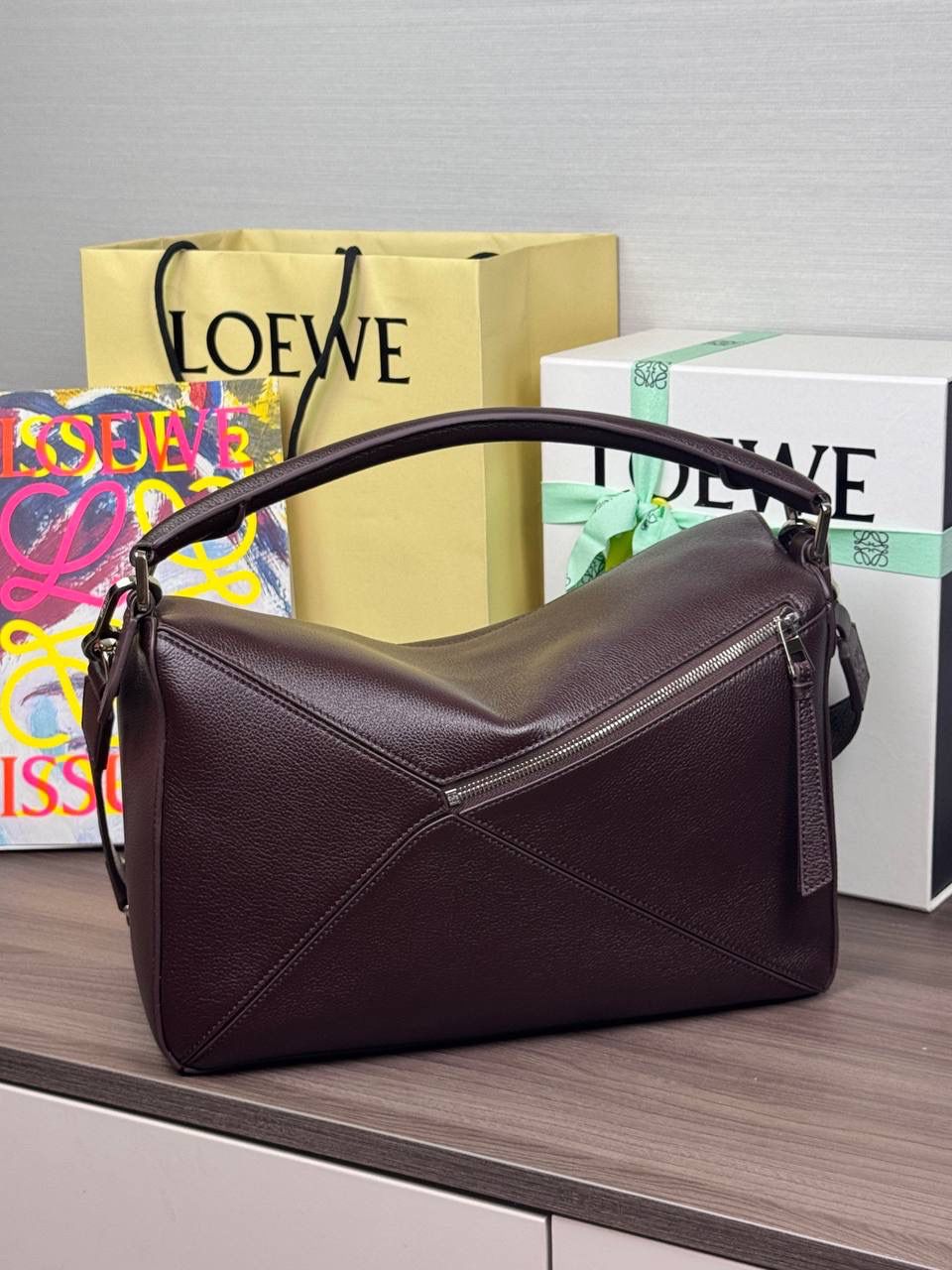 🎈【全钢】大号鹿皮𝘗𝘶𝘻𝘻𝘭𝘦* ——【👉🏻牛血色到货✅】 尺寸：𝟑𝟐.𝟓-𝟏𝟒.𝟓-𝟐𝟑.𝟓𝐜𝐦 编码：260403 【配全套包装】 ❤️经典拼图系列•不规则立体几何设计•最具辨识度的立体廓形和几何美学•顶级进口皮搭配德国沙菲线•独家定制五金•𝗬𝗞𝗞拉链拉头。 ❤️该款大号采用鹿皮革制成•绒面内里•搭配一条可拆卸可调节的皮肩带•肩背斜挎或手提多样化背法。