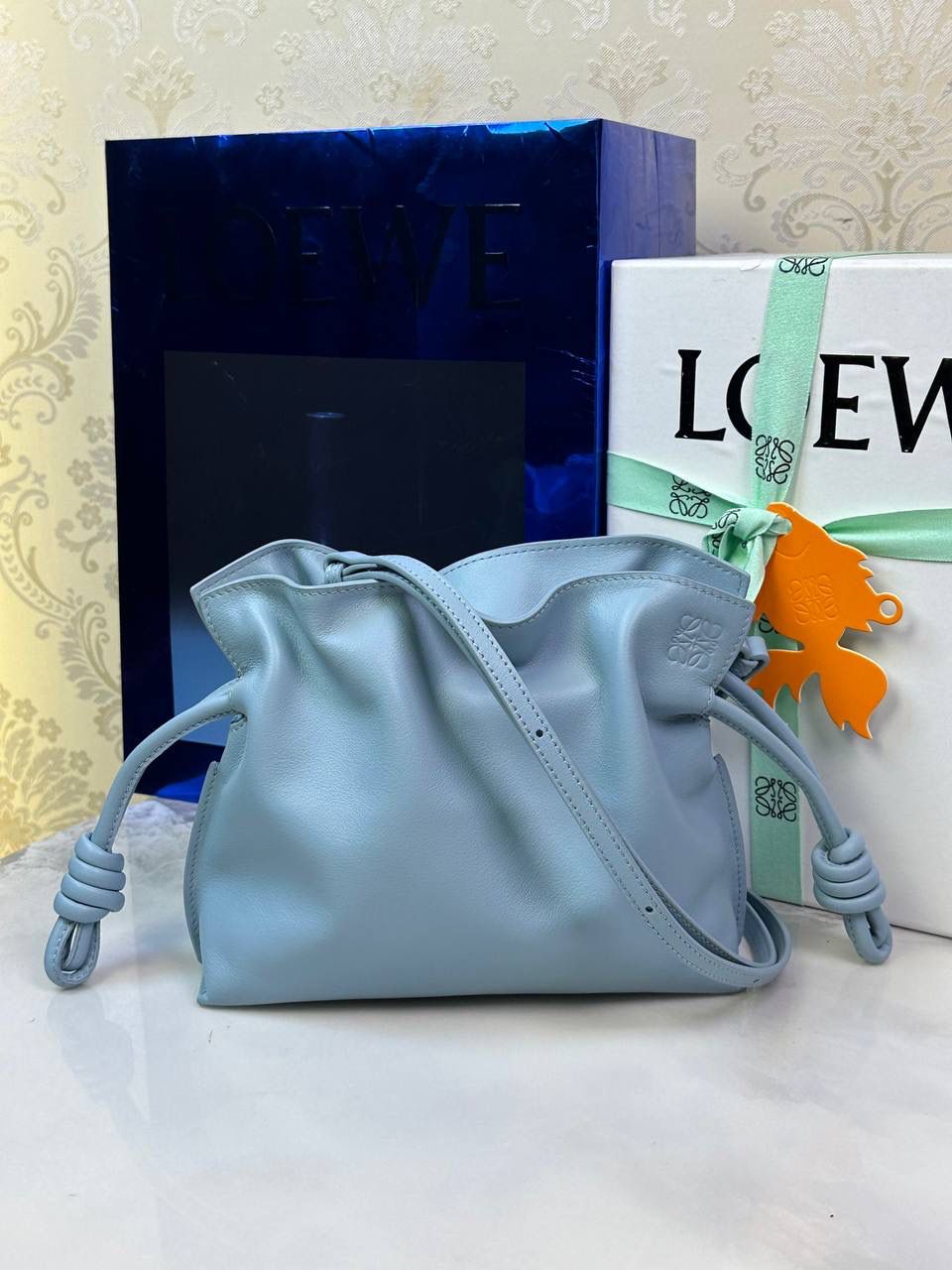 Flamenco clutch-NEW ✦迷你✦ 尺寸：𝟐𝟐.𝟓-𝟏𝟖-𝟗𝐜𝐦 型号：052030灰蓝色 ❤️mini flamenco clutch bag 可手拿亦可优雅斜挎 云朵般温暖亦轻盈的造型如此简单，💯耐看💯不会out的款式！ ❤️包袋采用进口小牛皮，手感如羊皮般细腻柔软，却比羊皮更加结实耐用，麂皮内衬 ❤️品牌标志性绳结设计，收紧袋口就是小福袋造型，超Q，看着不大实际超会装😇