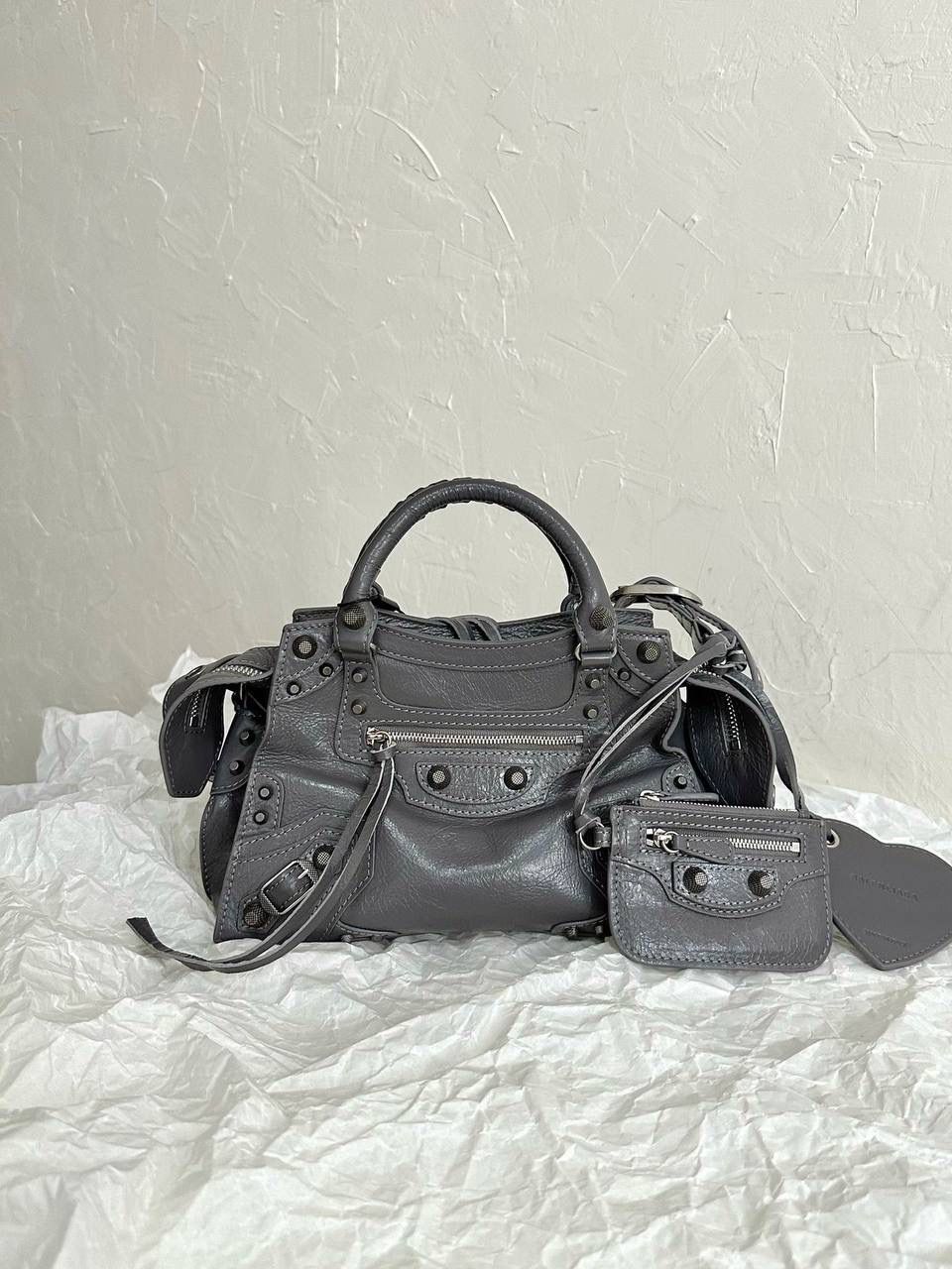 neo cagole 机车包xs 灰银色🌪️ 首先声明，我爱一切机车元素 无论是le cagole还是这只neo 喜欢大容量的姐妹冲这只 油蜡皮的不规则摔纹配上大量的五金配件 还有流苏拉牌➕爱心镜子➕零钱包挂件 极繁的魅力由此而来～ 辣妹酷妹冲冲！ 26×17.8×11.4cm700940m